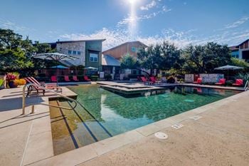 A resort style pool with lounge chairs and umbrellas
